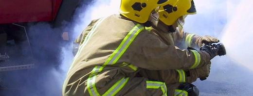 A close-up of 2 firefighters holding a fire hose during training