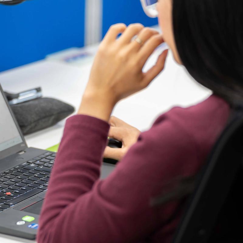 A female C5 Team member works on her laptop at her desk