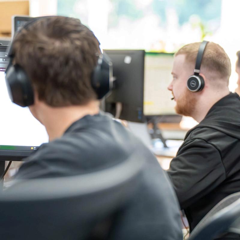 Several IT Services C5 Team Members working on their laptops and additional monitors at their desks in the office