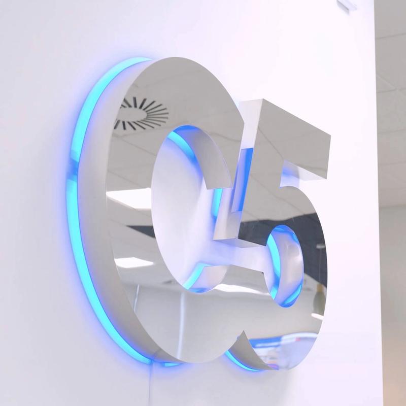 A Photo of a chrome C5 logo on a white office wall